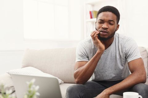 Young african-american man having toothache at home