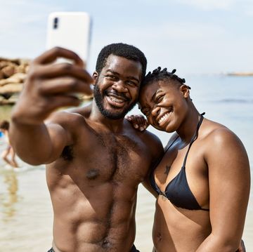 couple wearing swimwear making selfie by the smartphone at the beach