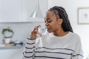 young african american woman drinking water from glass at home