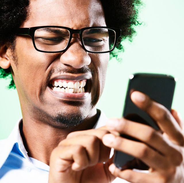 young afro haired nerd grimaces at cellphone he holds