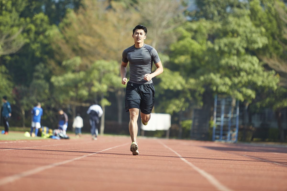 young asian athlete training on running track