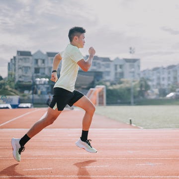 young asian chinese man athlete training on Mountaineering running track in the morning at track and field stadium