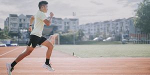 young asian chinese man athlete training on running track in the morning at track and field stadium