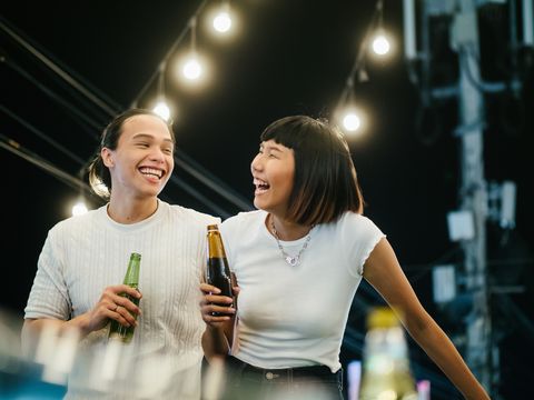 young asian couple toasting with beer at rooftop party