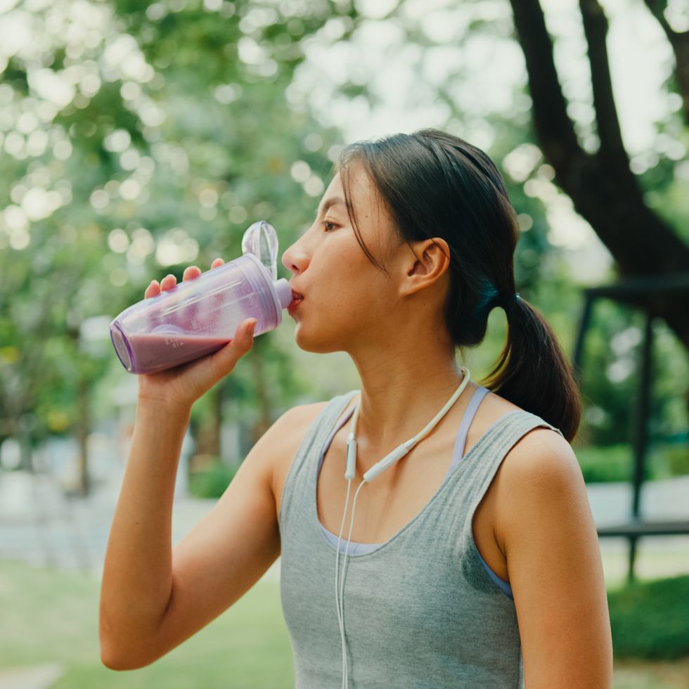 young asian female athlete runner drinking protein shake after exercise workout in urban park diet and healthy food workout exercise