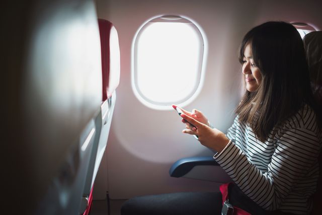Young asian girl using smart phone on commercial flight
