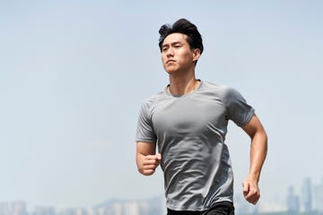 young asian man athlete running on beach