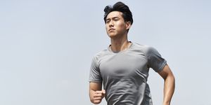 young asian man athlete running on beach