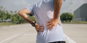 a young asian man has pain after exercise, sport injury, man with back pain