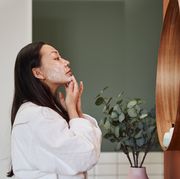 young asian woman applying moisture cream at her face