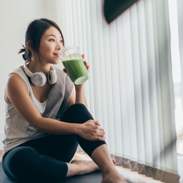 young asian woman drinking green smoothie after yoga