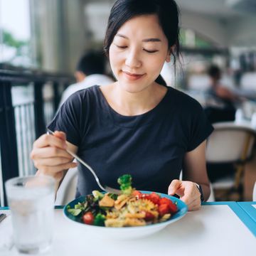 young asian woman enjoying a healthy meal for lunch she is having fresh and colourful vegan salad bowl with organic greens and fruits at a vegan restaurant healthy eating, go green lifestyle