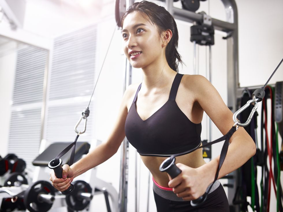 young asian woman exercising in gym using equipment