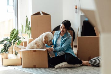 young woman having fun with her dog while unpacking cardboard boxes in the living room