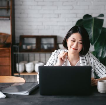 young asian woman having online business meeting, video conferencing on laptop with her business partners, working from home in the living room