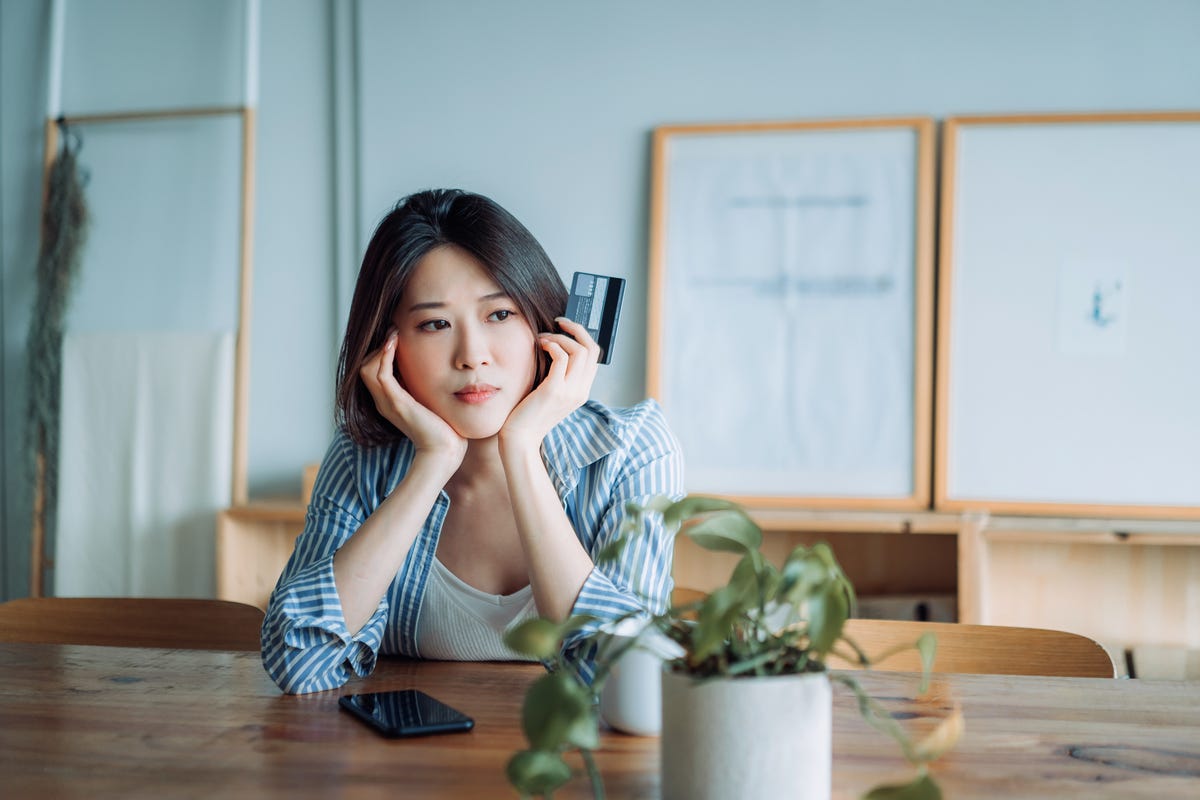 young asian woman having problems with her credit card and looking worried financial issues, banking, finance, credit card fraud