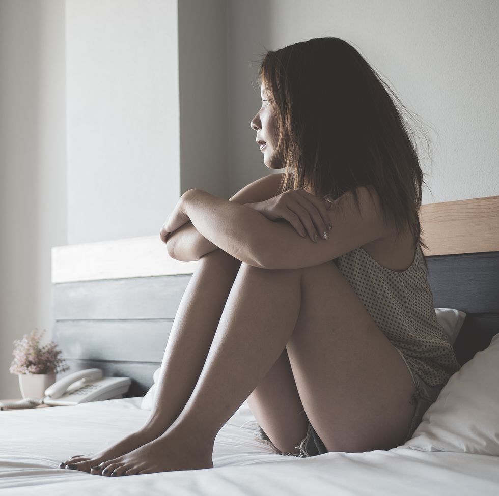 young asian woman in sad sitting on a bed