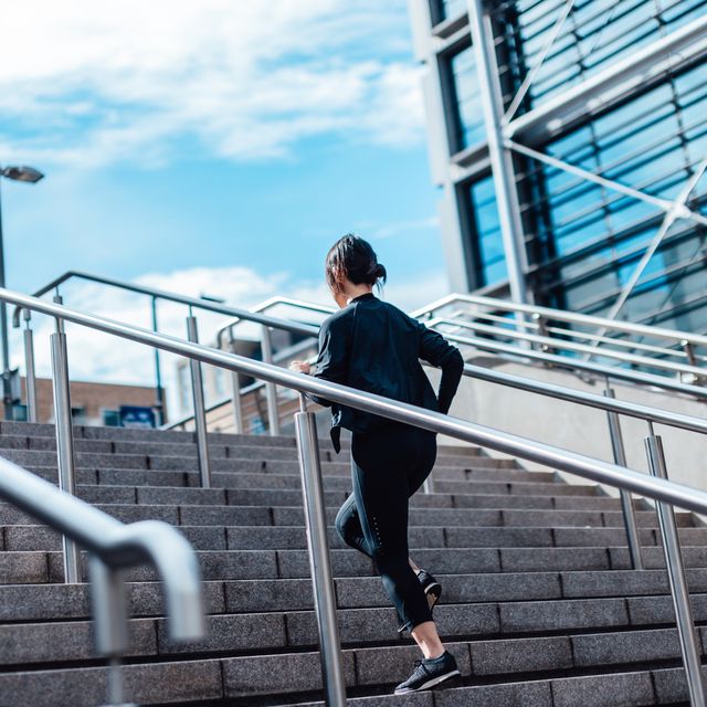 young asian woman running upstairs in finance district
