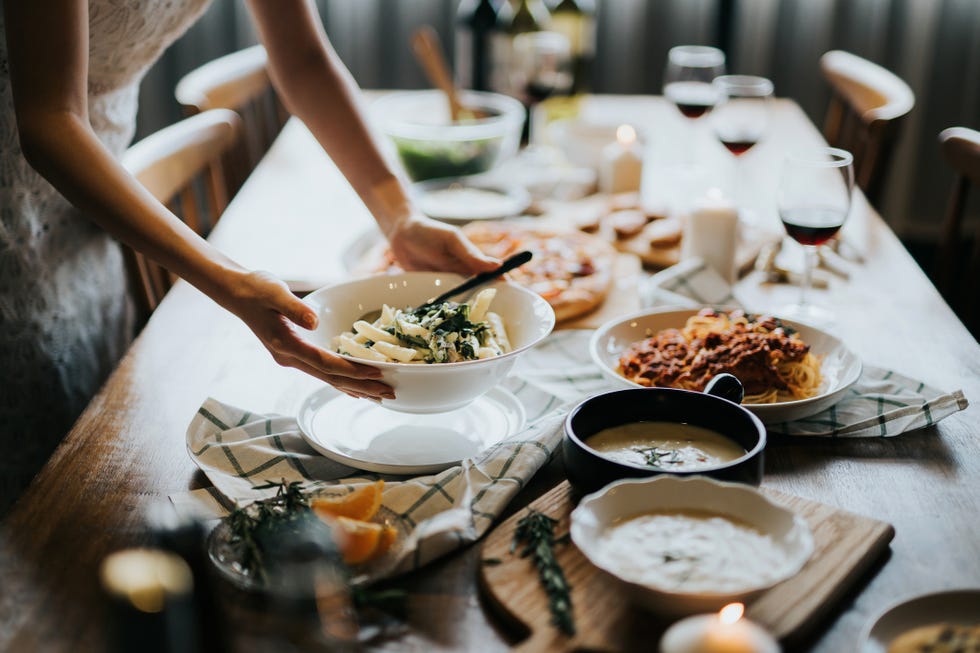 young asian woman setting the table and serving food and wine ready for party with friends at home