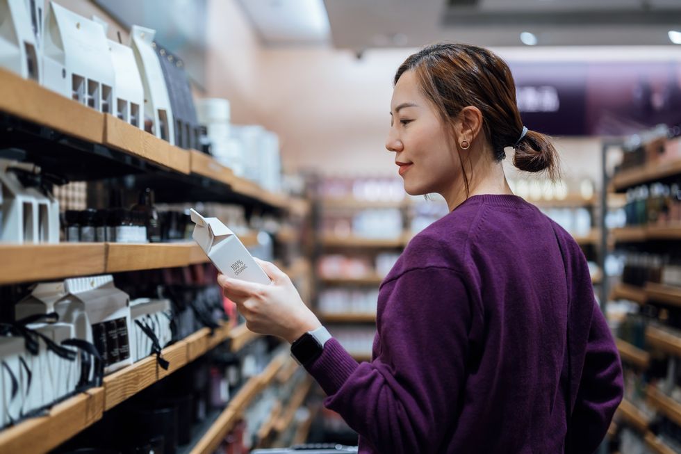 young asian woman shopping for natural beauty products in organic health and beauty store looking at the ingredients of the skincare package personal skincare products health and wellness concept sustainable lifestyle