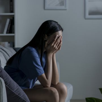 young asian woman sitting on sofa at home feeling sad tired and worried suffering depression in mental health