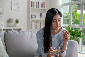 young woman taking pill and vitamin in the living room