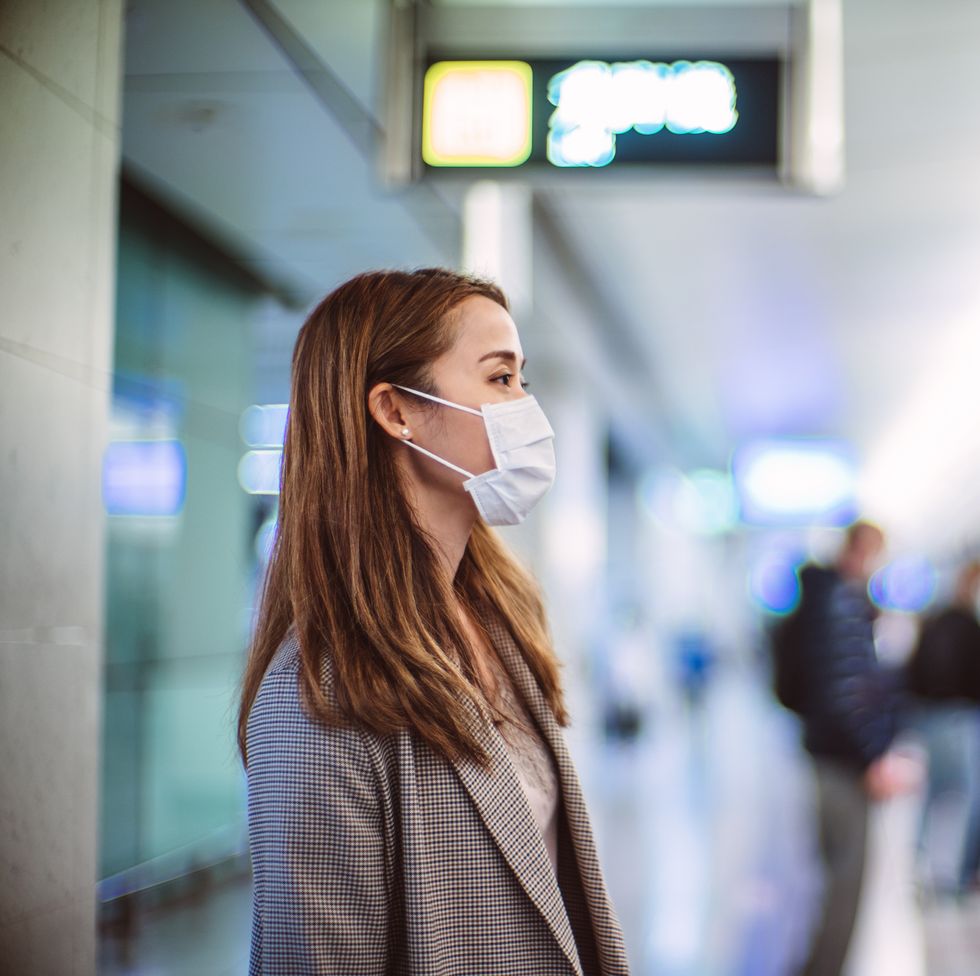 young asian woman with protective face mask commuting in the city and waiting for train in platform