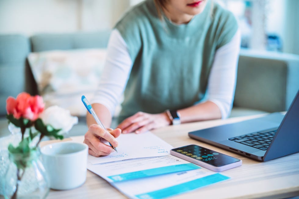 young asian women managing home finance using laptop  smartphone she is working with household utility bill and calculating expenses at home