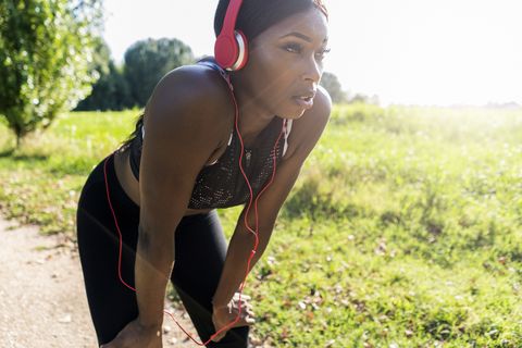 young athlete in nature, listening music with headphones, preparing for training