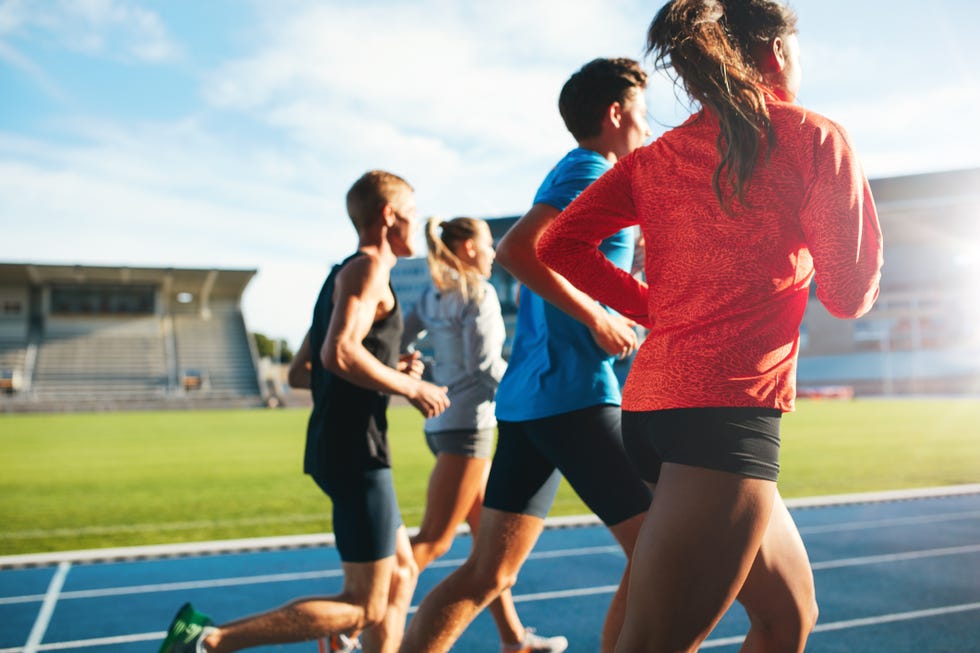 young athletes running on race track in stadium