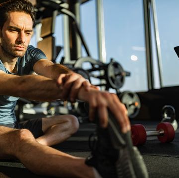 young athletic man doing stretching exercises in a gym.