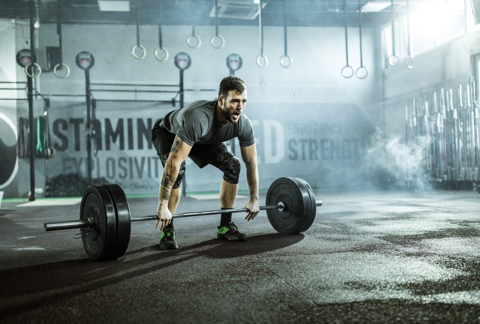 young athletic man exercising deadlift in a gym