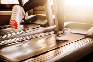 young athletic man running on treadmill legs close up