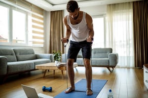 young athletic man training with stretching band at home