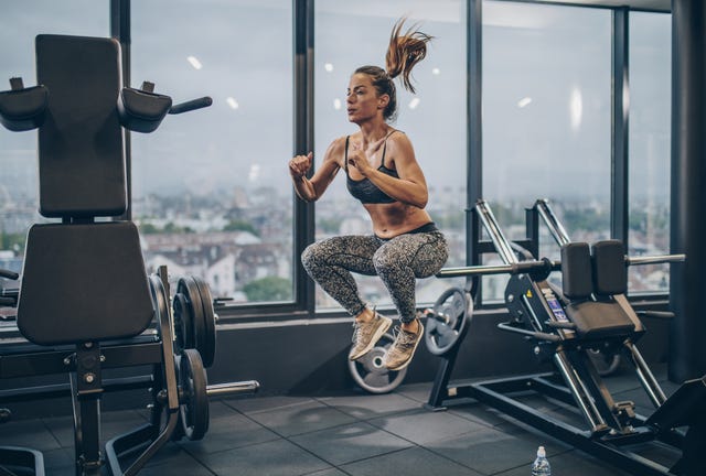 Young athletic woman exercising jumps in a health club.