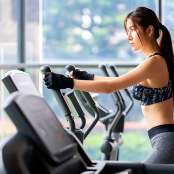 young athletic woman exercising on cross trainer machine cardio training at the gym