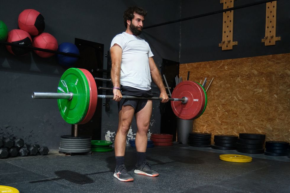 young bearded man doing deadlift exercise in a crossfit gym