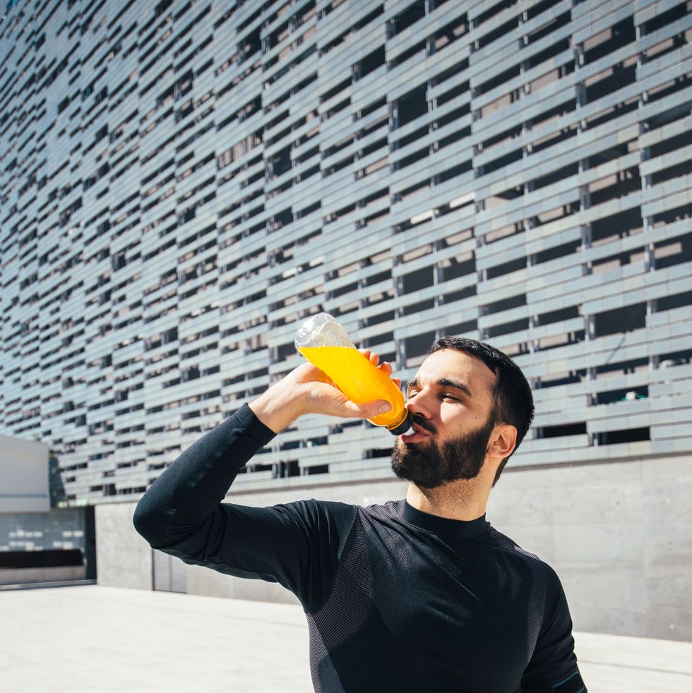 young beautiful man drinking an energy drink while training
