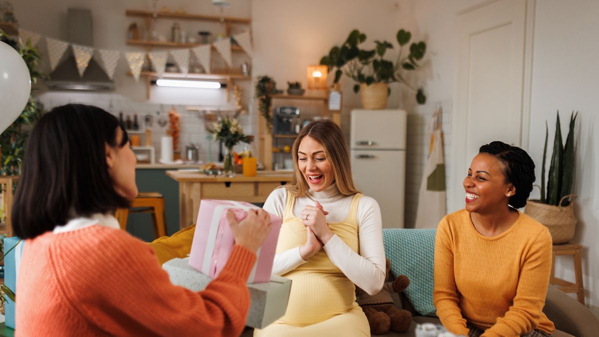 young beautiful pregnant woman getting presents on a baby shower party at her apartment
