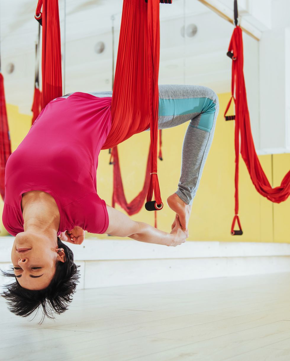 young beautiful woman practicing yoga fly with a hammock in the bright studio the concept of mental and physical health