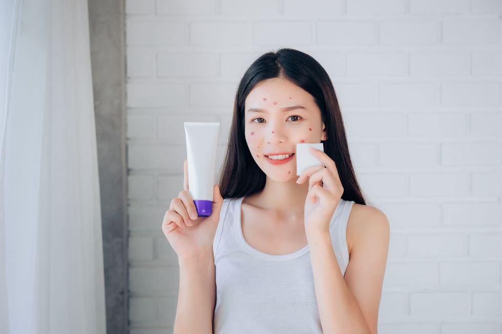 young beauty asian woman cleaning face with cotton and cleansing foam skincare for reduce acne problems her smile and happy morning in white bedroom