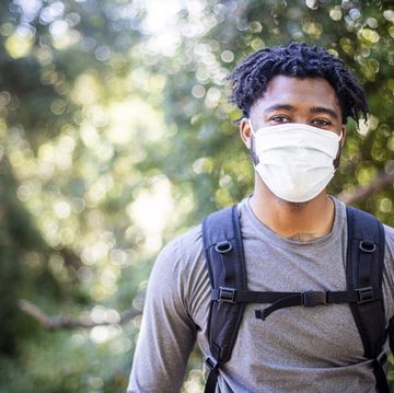 young black man wearing a face mask while hiking