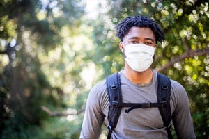 young black man wearing a face mask while hiking