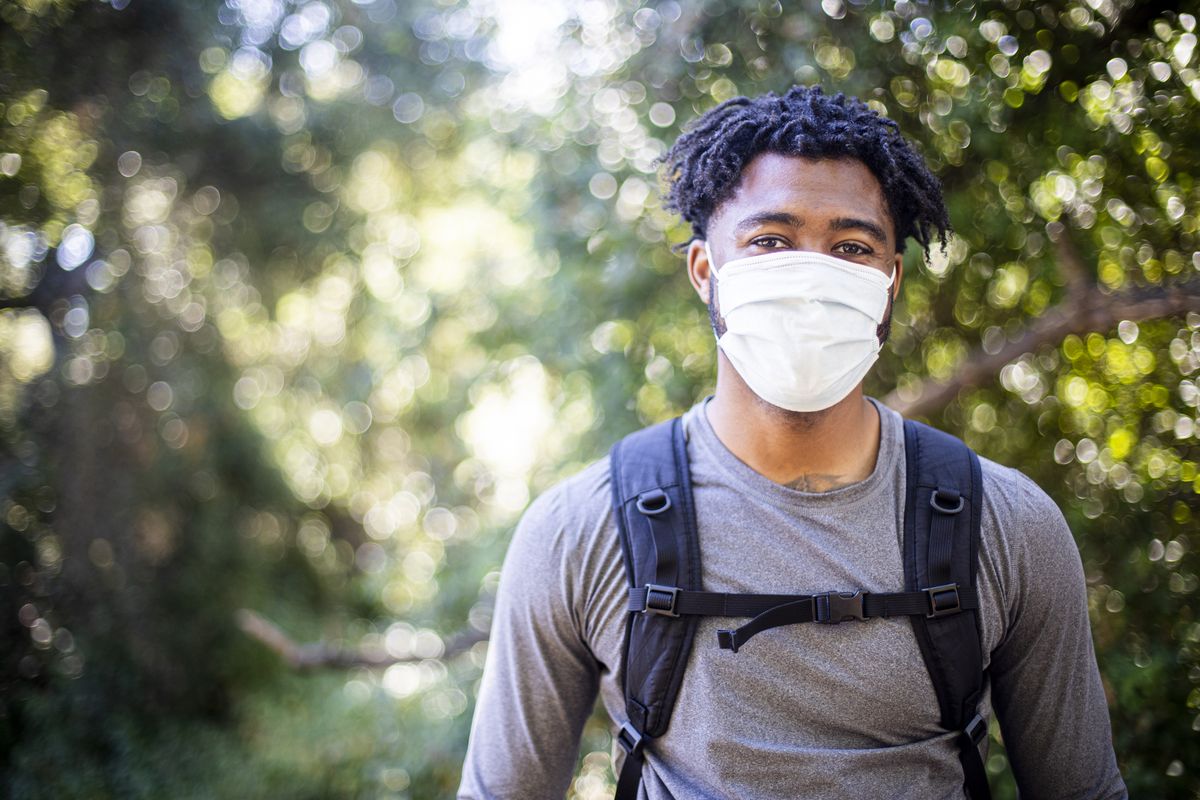 young black man wearing a face mask while hiking