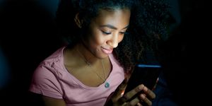 young woman texting on mobile phone at night