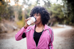 jonge vrouw drinkt koffie tijdens wandelen