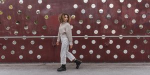 young blond woman walking by maroon metallic wall