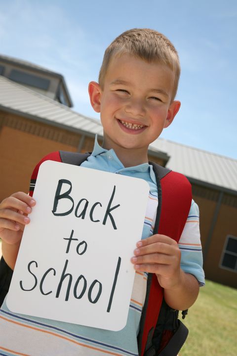 young boy holding a back to school sign outside