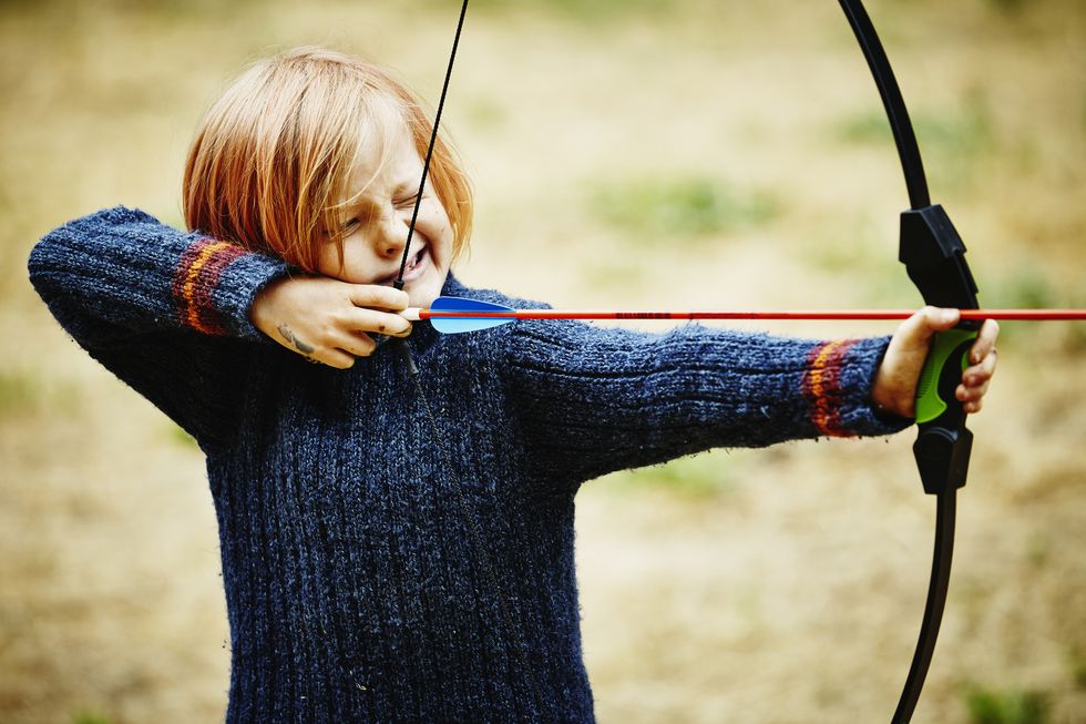 young boy learning to shoot bow and arrow