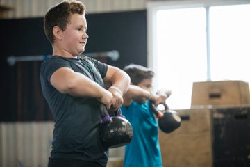 young boys lifting kettlebells at gym